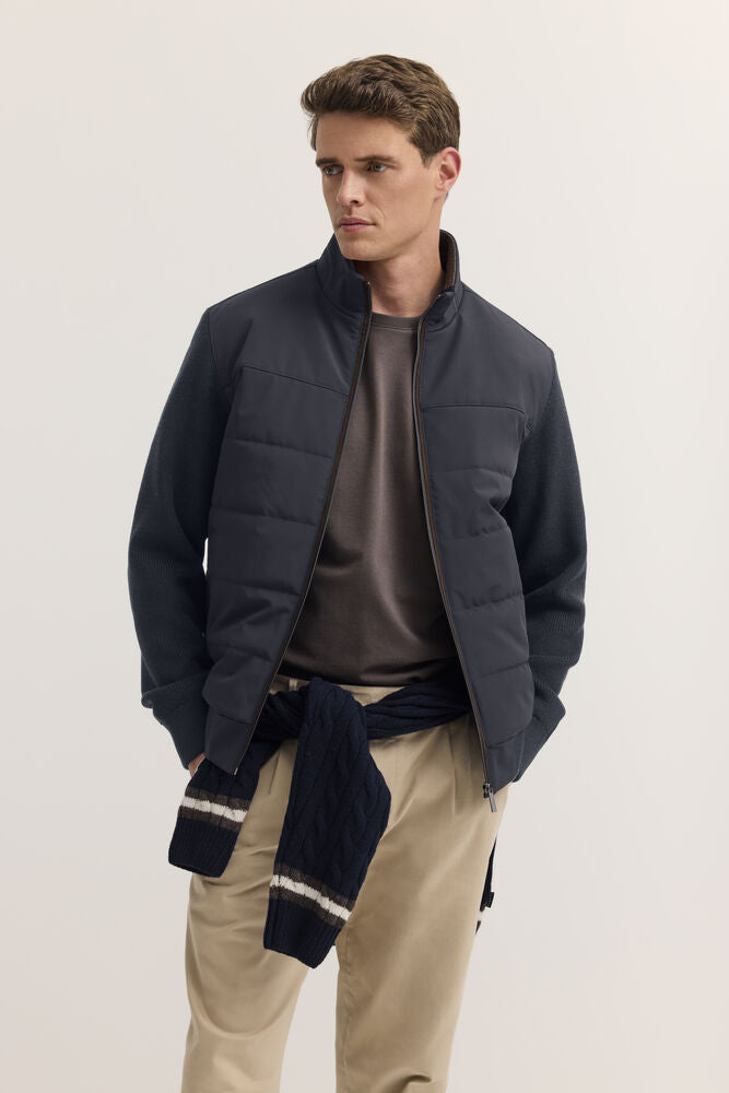 Navy blue cable knit cardigan with white and brown stripes on the cuffs, tied around the waist.
