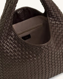 Mocha brown woven leather shoulder bag with a slouchy design, a woven handle, and a light brown interior with a zip pocket.
