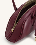 Deep claret shoulder bag with a smooth finish, gold-toned top zipper, matching claret zipper pull, and olive-green interior.