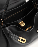 Black pebbled shoulder bag with an open top, gold-toned D-shaped buckle, gold-toned zipper, and ribbed hardware inside.