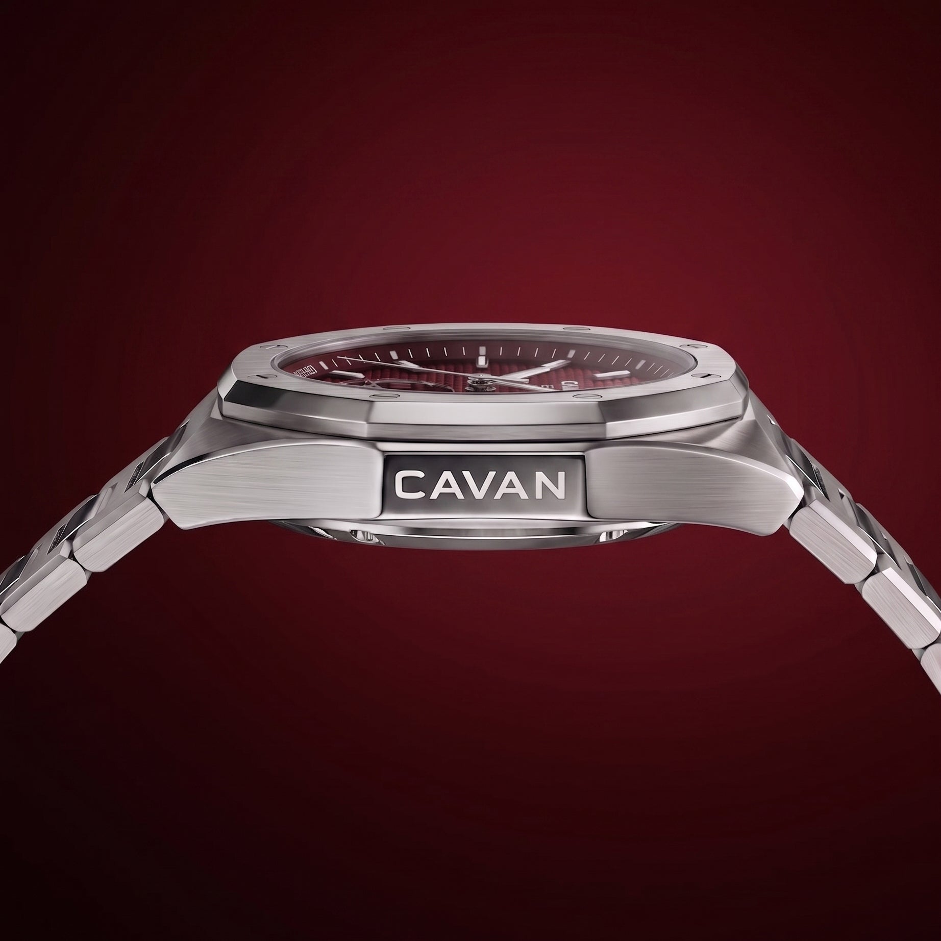 Silver-toned watch with an octagonal bezel, dark red textured dial, and a metal link bracelet. 'CAVAN' is engraved on the sid