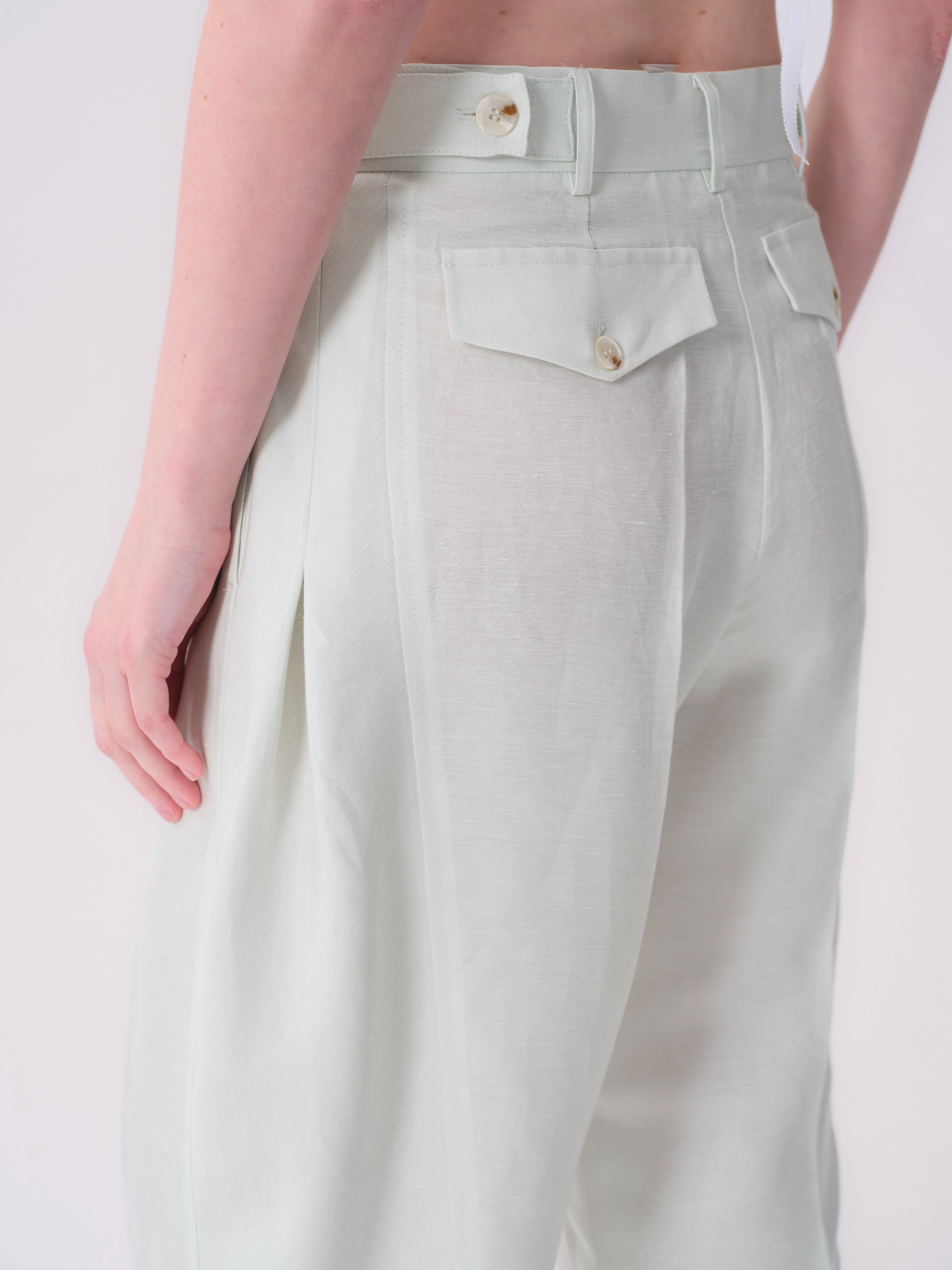 Pale mint green trousers with a high waist, belt loops, and two back flap pockets, each with a light brown button. Lightweigh