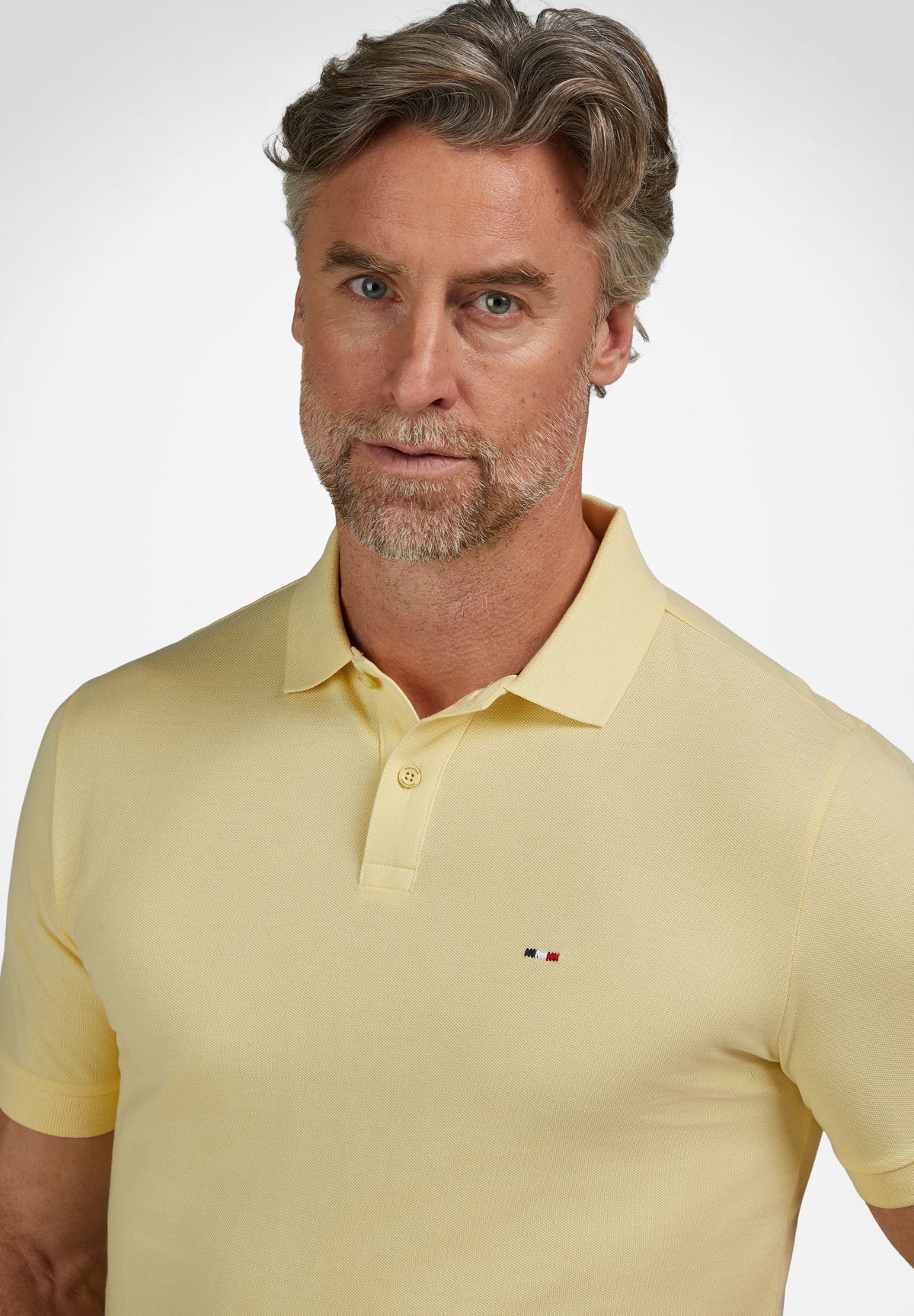 Light yellow pique knit polo shirt with a two-button placket, classic collar, short sleeves, and a small striped logo on the