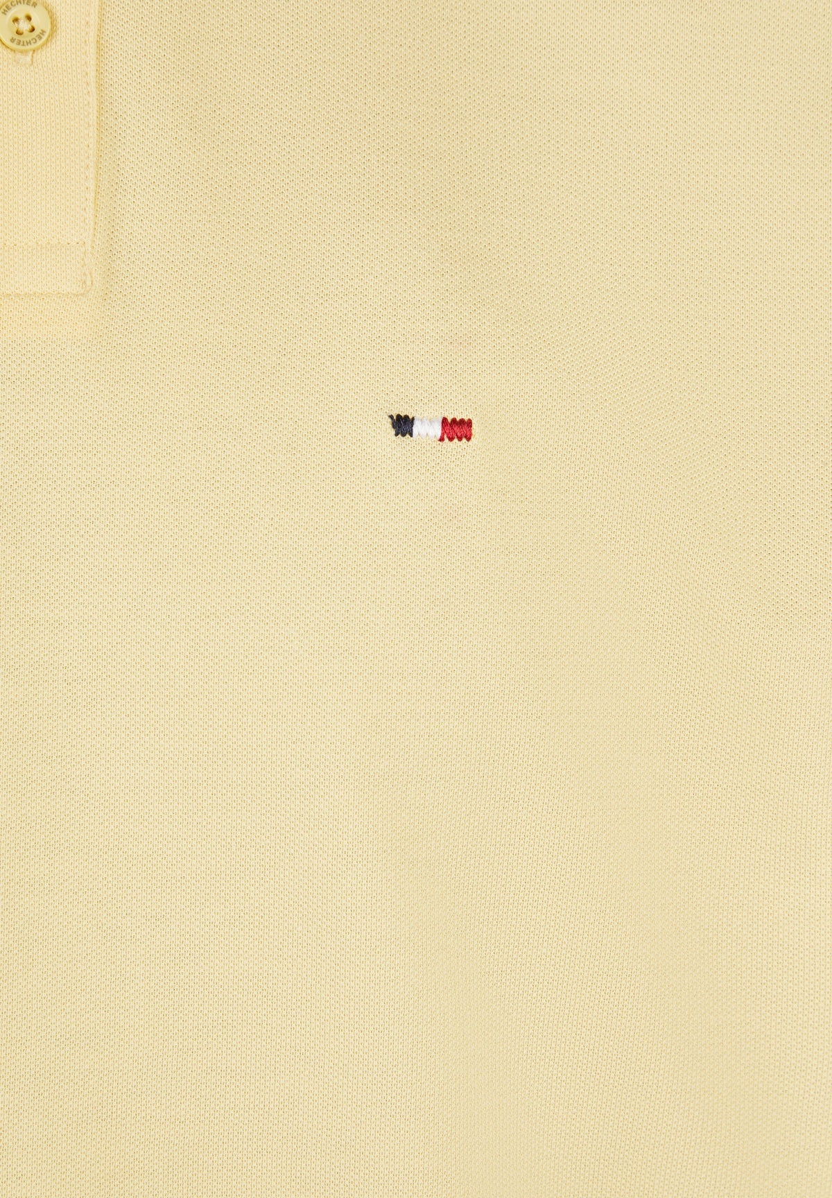 Vanilla pique knit polo shirt with a gold-toned button on the placket and a small embroidered blue, white, and red logo.