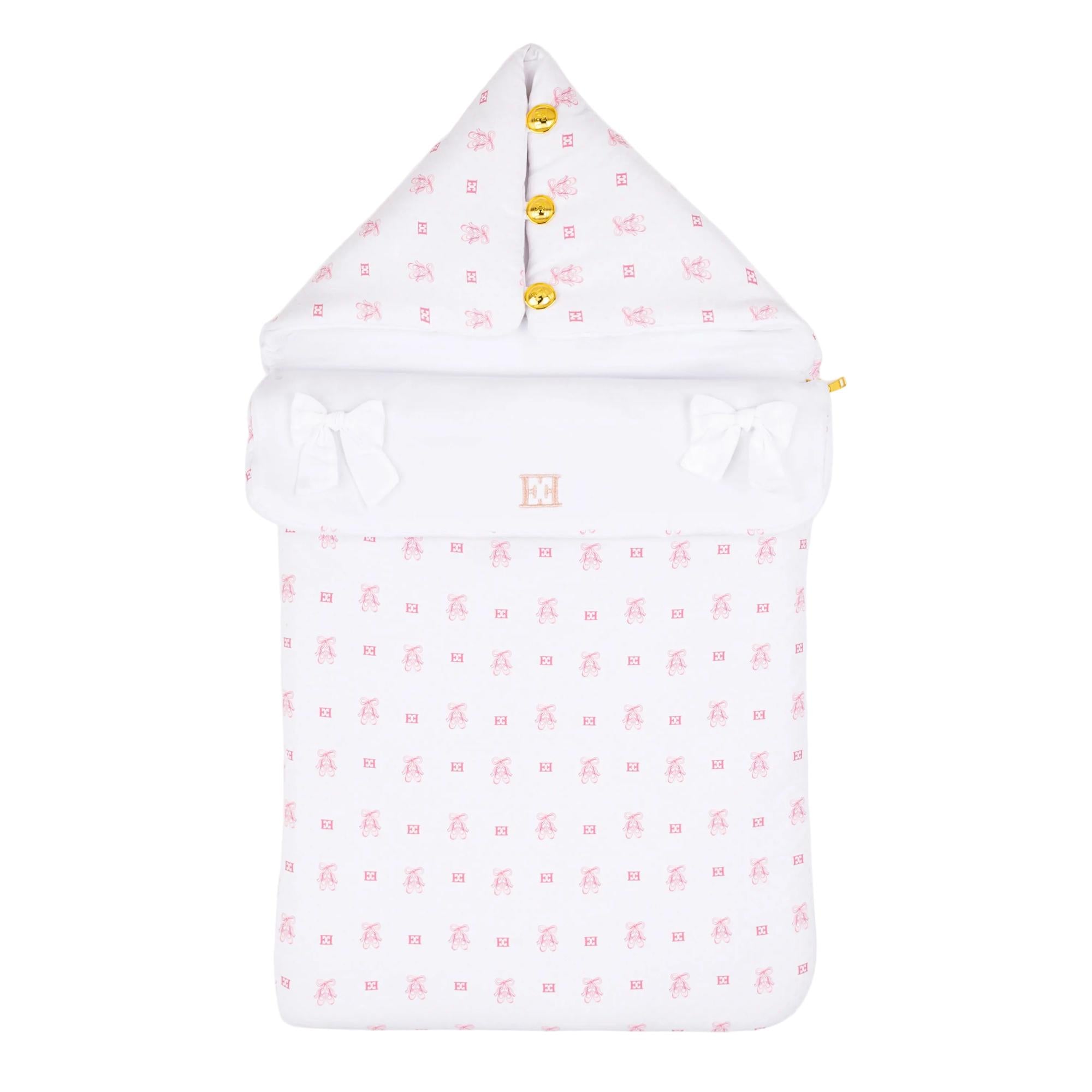 White baby nest with pink teddy bear and logo pattern, gold-toned buttons, and white decorative bows.