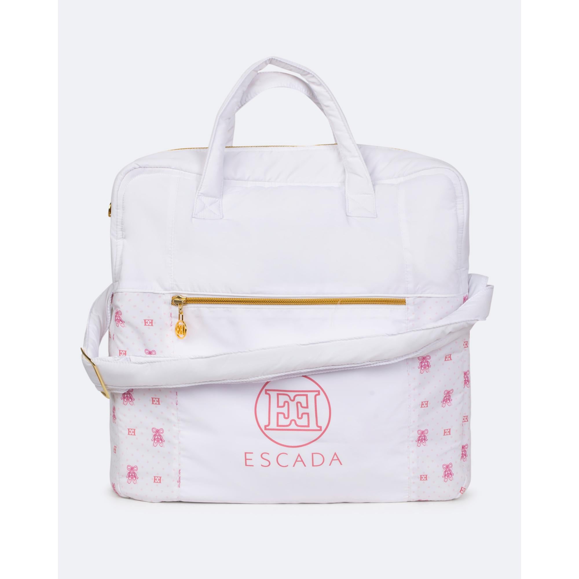 White changing bag with top handles, shoulder strap. Front has pink polka dot/ballet slipper print, pink Escada logo, and gol