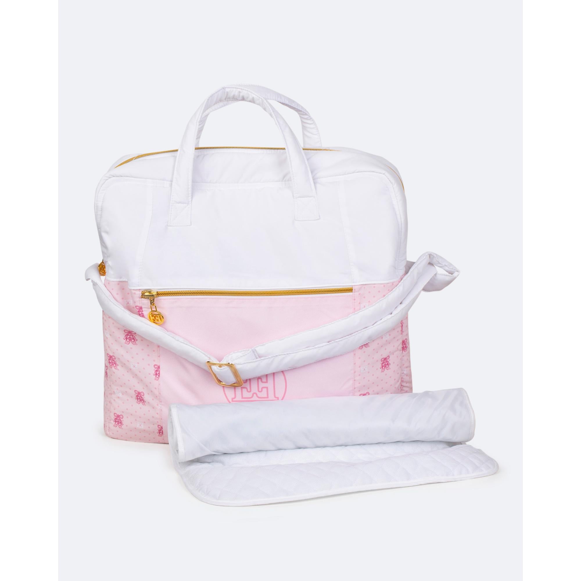 White and pink changing bag with bow pattern, polka dots, 'ECI' logo, gold-toned zippers, and a white quilted changing mat.
