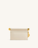 Off-white clutch with a rolled top flap, gold-toned spherical and cylindrical accents, and a gold-toned leaf pendant.