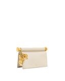 Cream clutch with a gold-toned cylindrical top handle and two large, textured gold-toned leaf pendants.