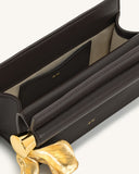 Dark brown structured clutch with light interior, gold-toned "JW PEI" logo, and a wavy gold-toned metal pendant.