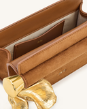 Dark brown faux suede clutch with smooth trim, light lining, and a large wavy gold-toned metal pendant embellishment. JW PEI