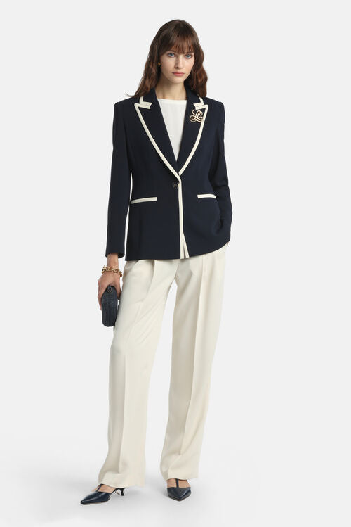 Navy blue blazer with off-white trim on notched lapels, single button closure, and two welt pockets. Features a gold-toned "L