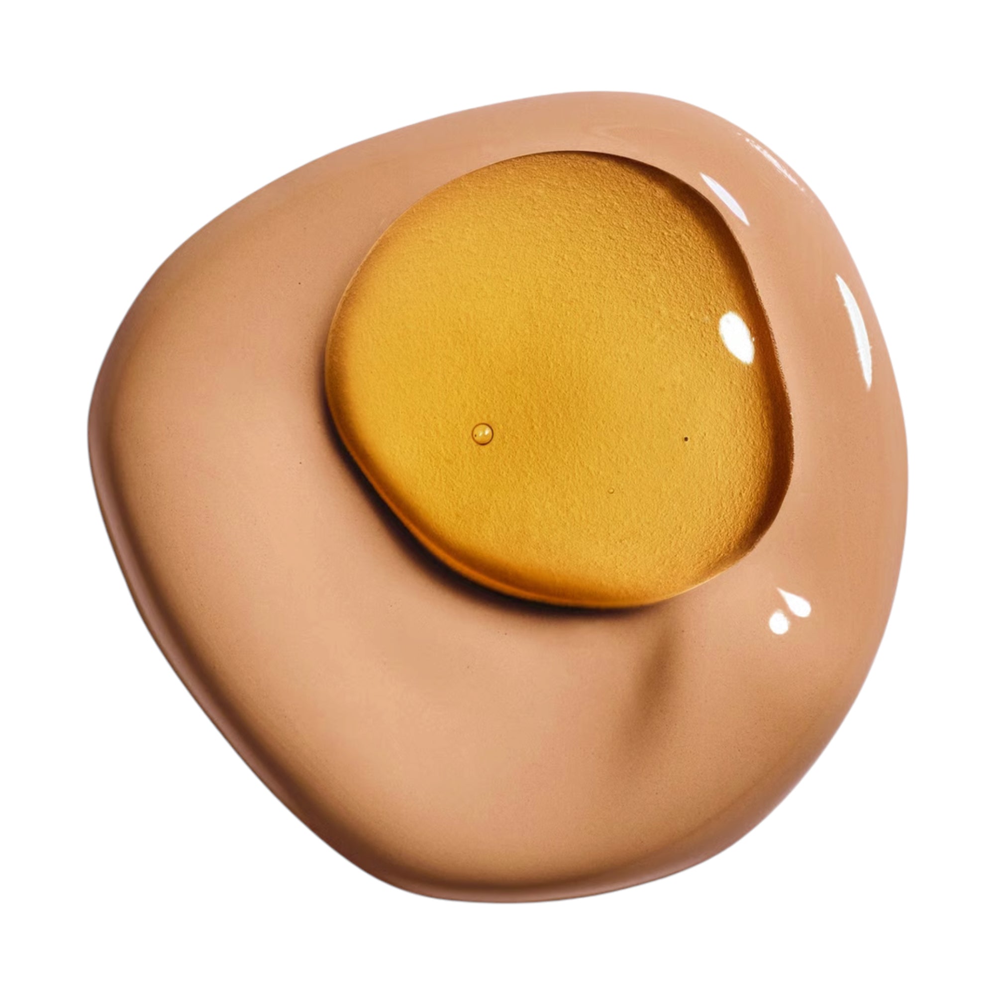 A swatch of light brown foundation with a golden, shimmery liquid layered on top, showing reflections.