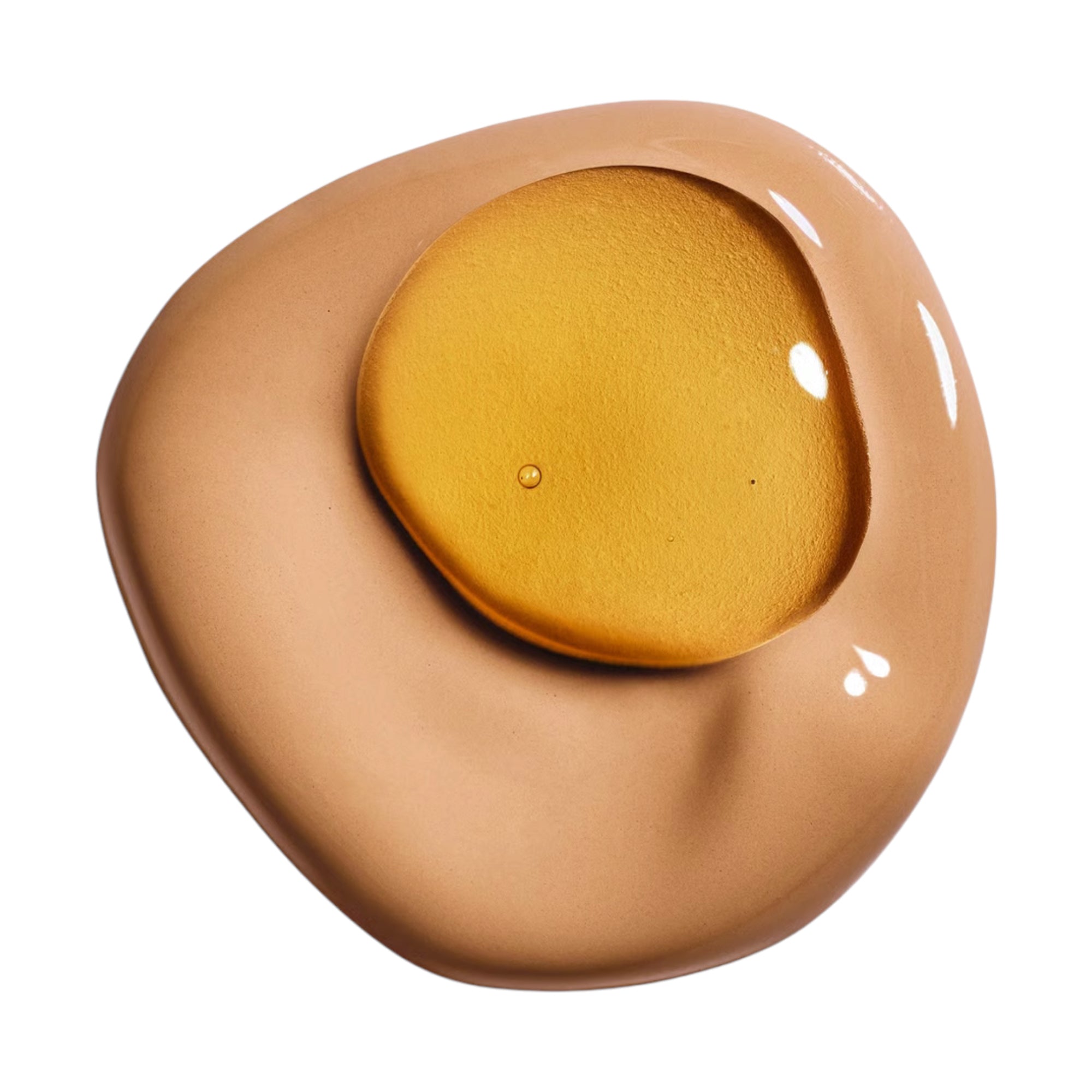 A light brown liquid foundation with a pool of golden, shimmery liquid on top, showing small bubbles and reflections.