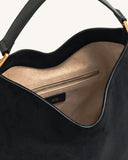 Black faux suede shoulder bag with a curved shape, black strap, gold-toned hardware, and a tan interior with a zipper pocket.