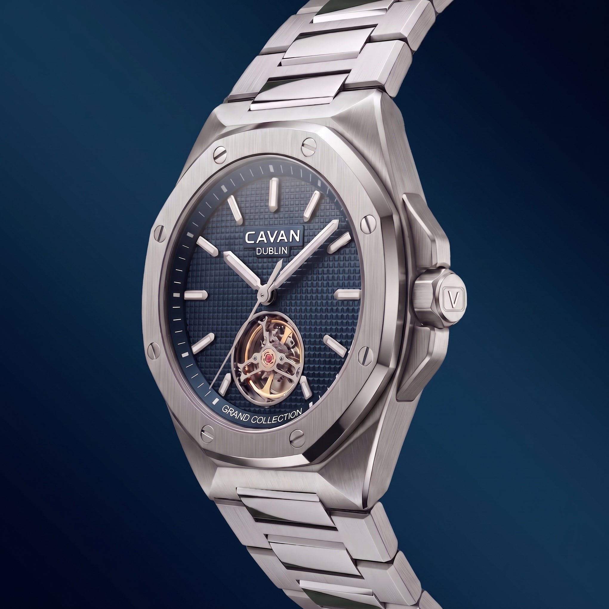 Silver-toned watch with an octagonal case, dark blue textured dial, silver-toned hands and markers, and an exposed gold-toned