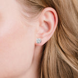 A round stud earring with a clear faceted stone surrounded by smaller pave stones in a silver-toned setting.