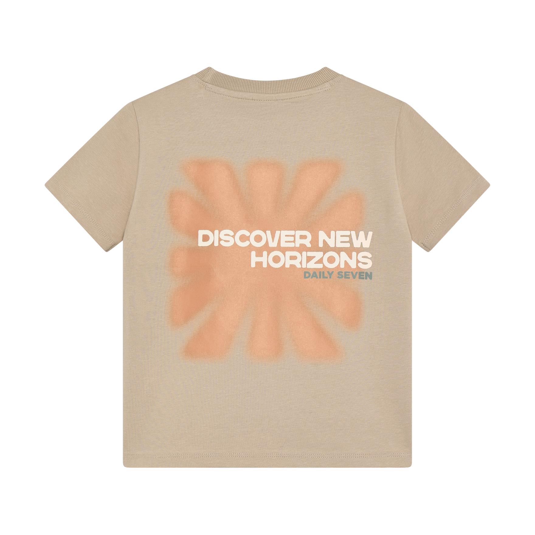 Beige short-sleeved crew neck t-shirt with a faded peach starburst graphic and white text 'DISCOVER NEW HORIZONS DAILY SEVEN'
