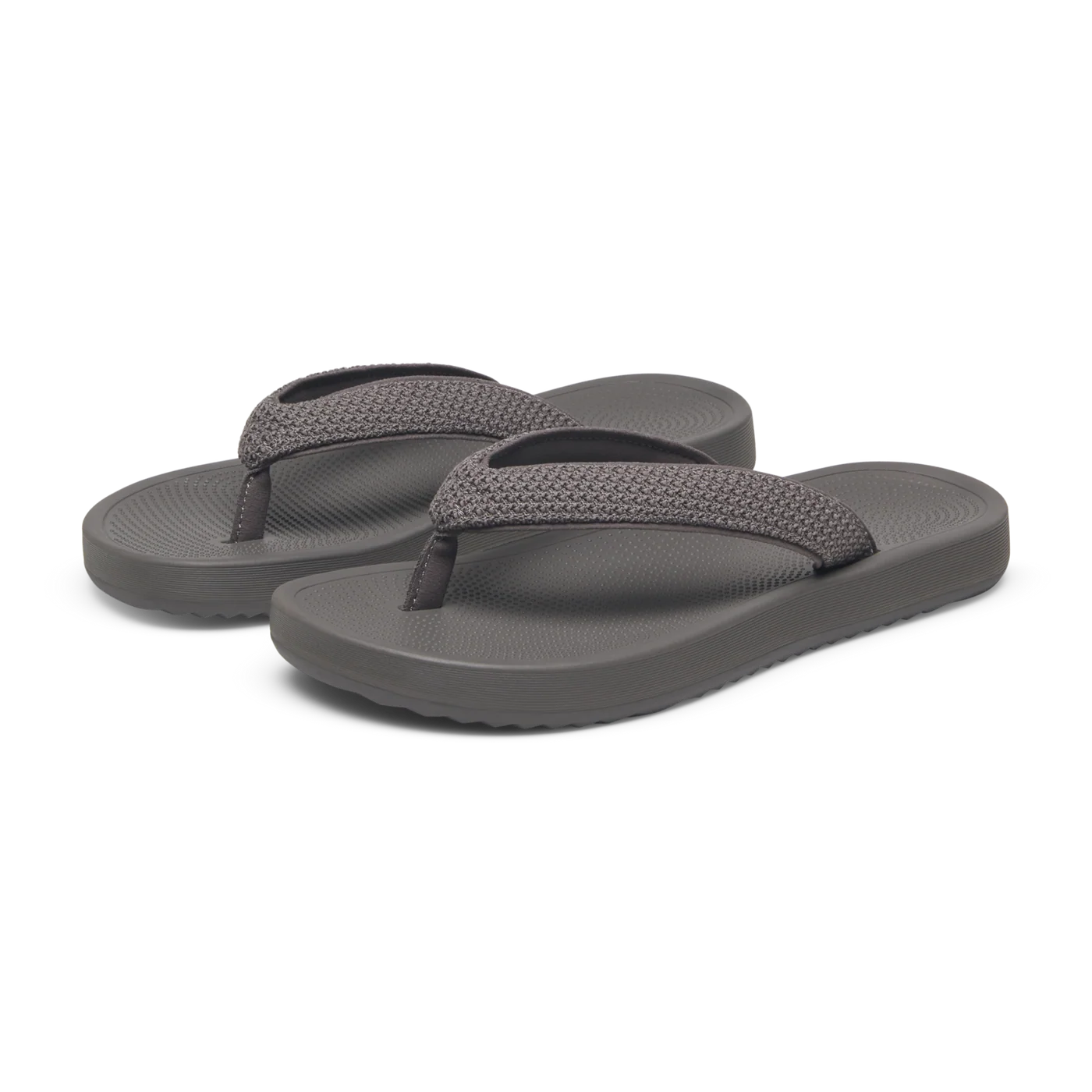 A pair of grey flip-flops with textured wide straps and smooth toe posts. The footbed has a subtle pattern, and the sole is s
