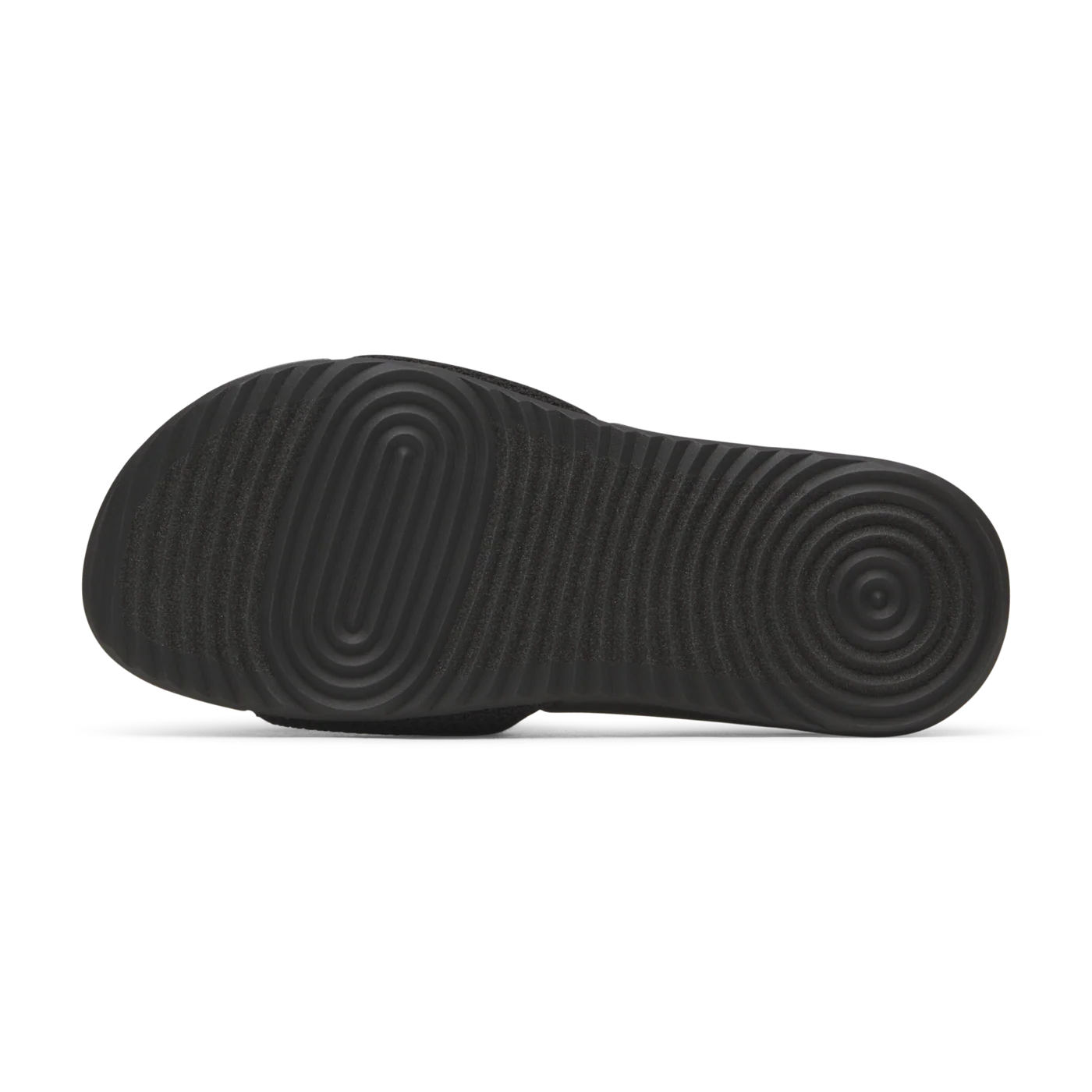 Black slide sandal, bottom view. Sole features textured concentric oval and circular ridges with horizontal grooves.