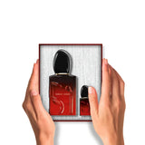 Red-bordered box with two Giorgio Armani Sì perfume bottles. Larger bottle: red-to-black ombre, black cap. Smaller bottle: re
