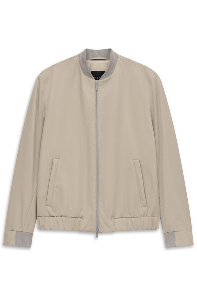 Beige blouson jacket with a light grey ribbed stand-up collar, cuffs, and hem. Features a full-zip front and two vertical wel