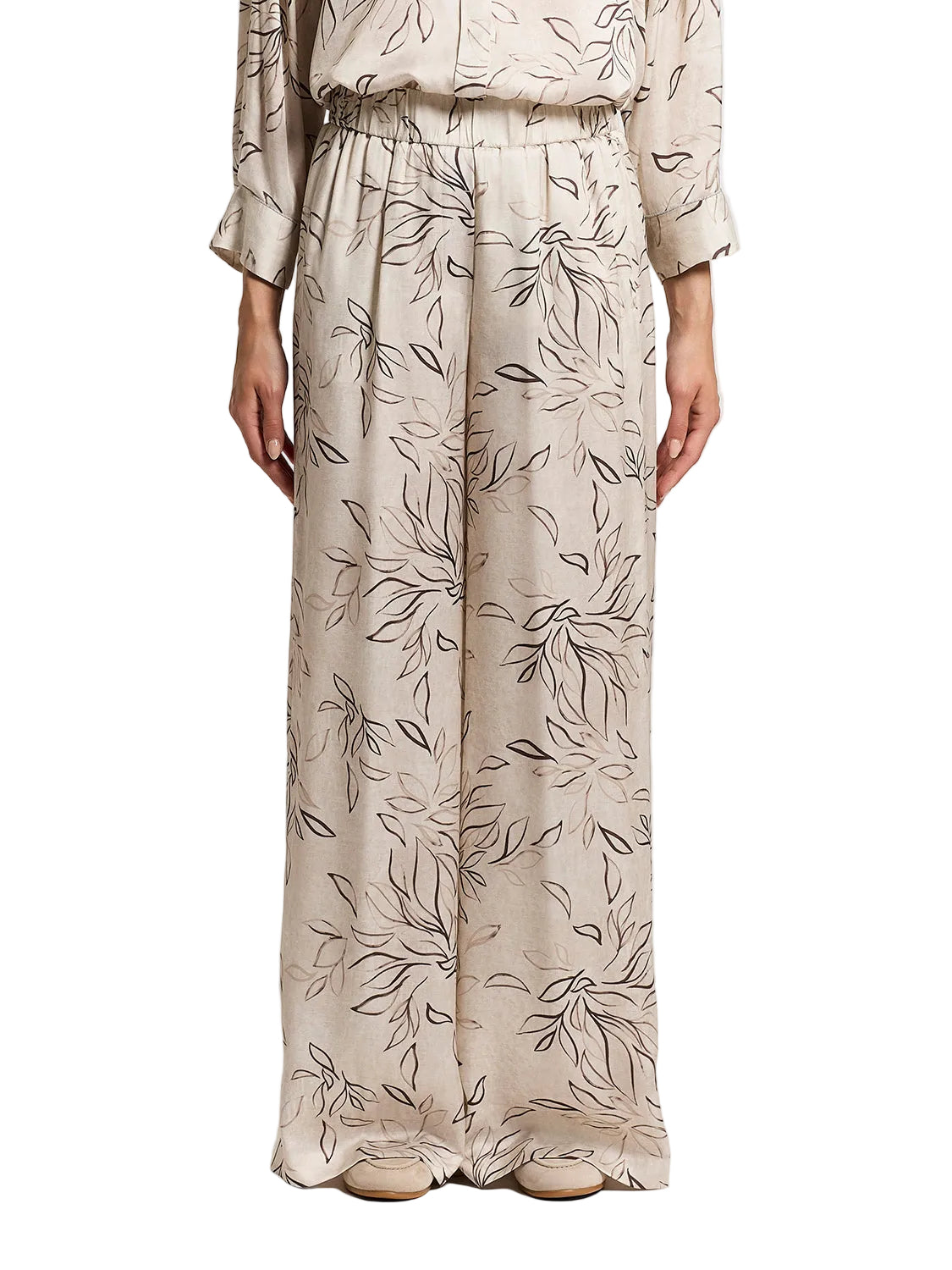 Beige wide-leg trousers with an all-over dark brown and light brown botanical leaf print and an elasticated waistband.