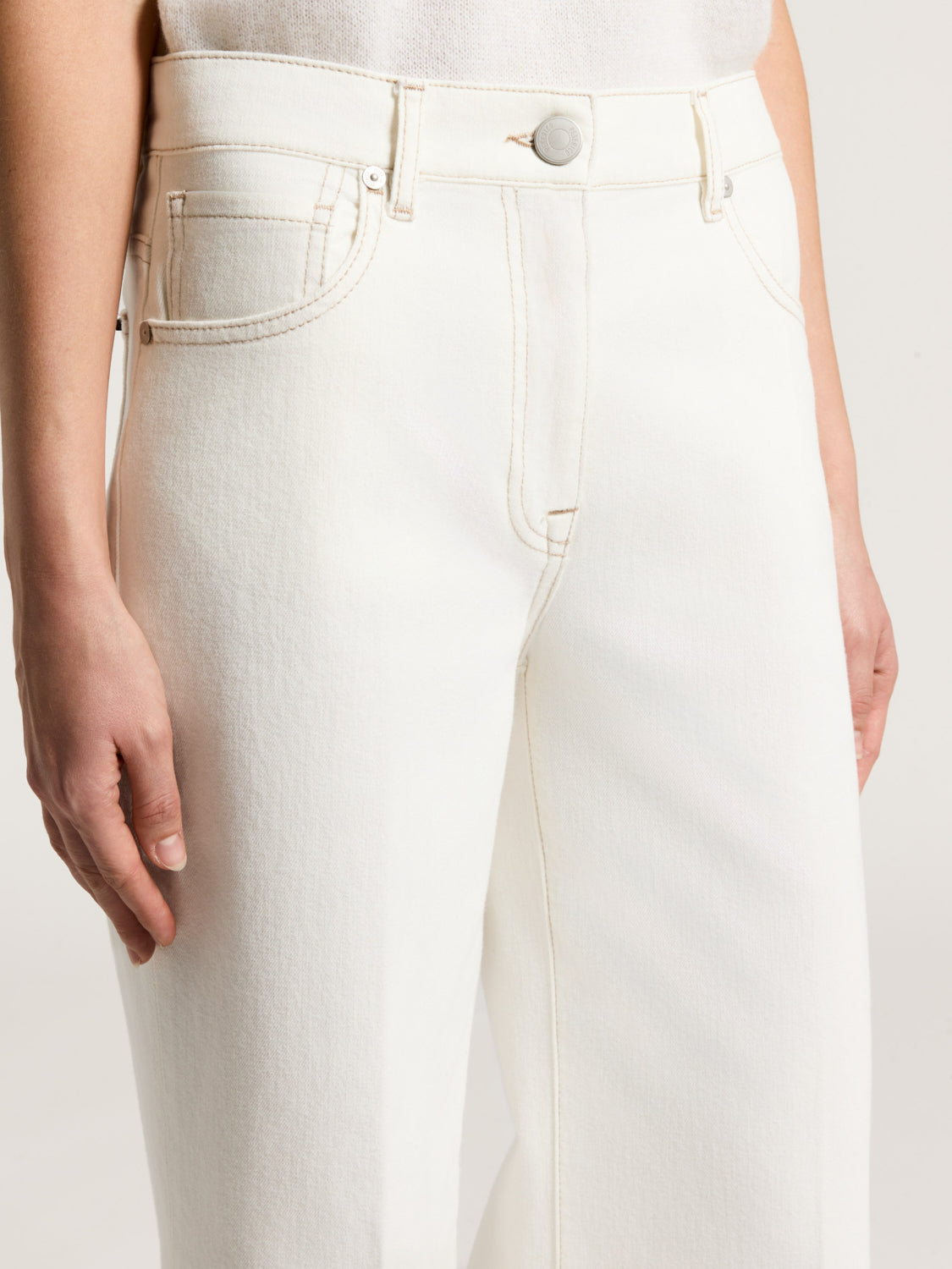 Comet White high-waisted trousers with contrast tan stitching, silver-toned button, belt loops, and front curved pockets.