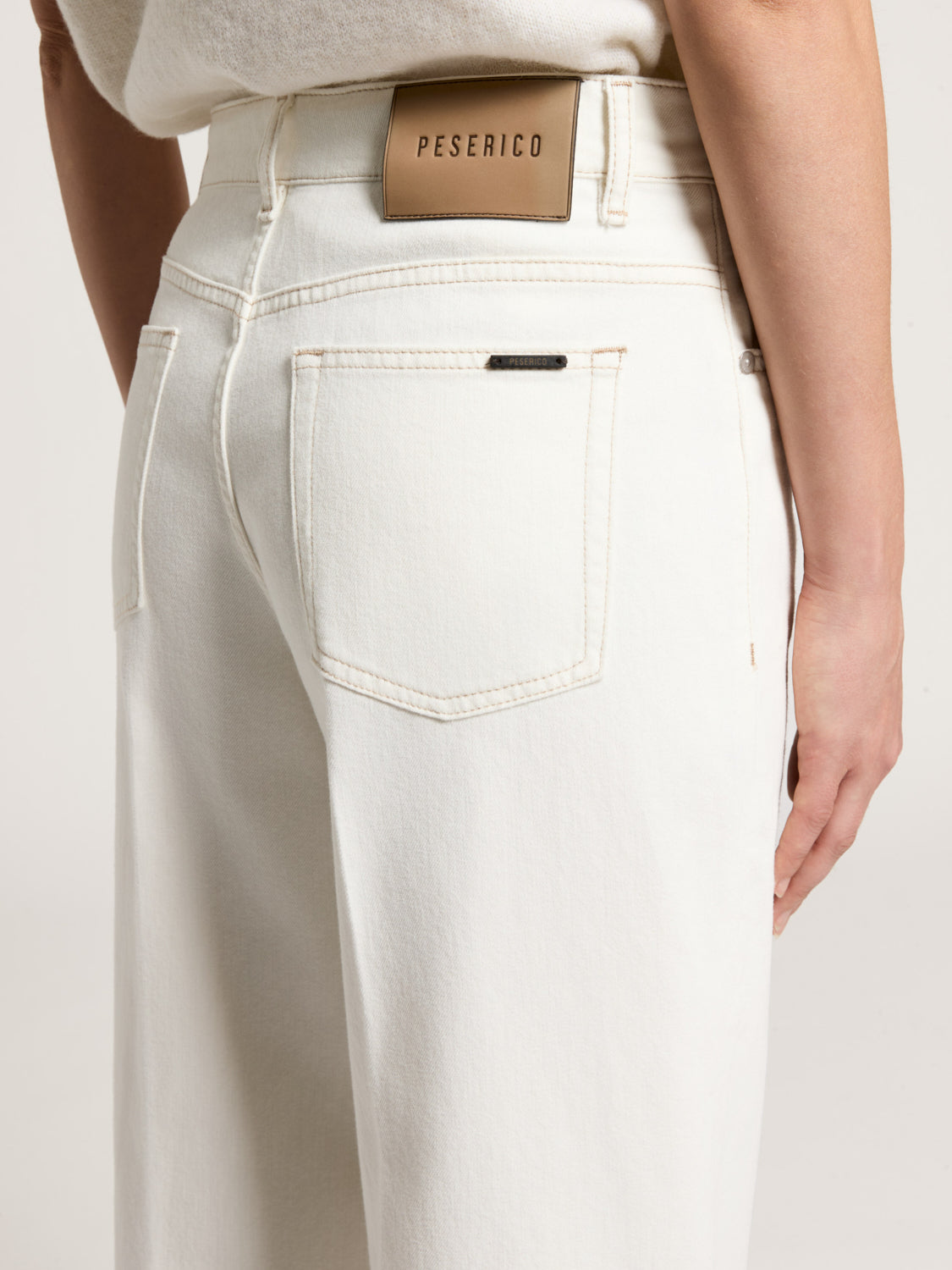 White trousers, back view, with a light brown 'PESERICO' waistband patch, a visible back pocket with tan stitching and a blac