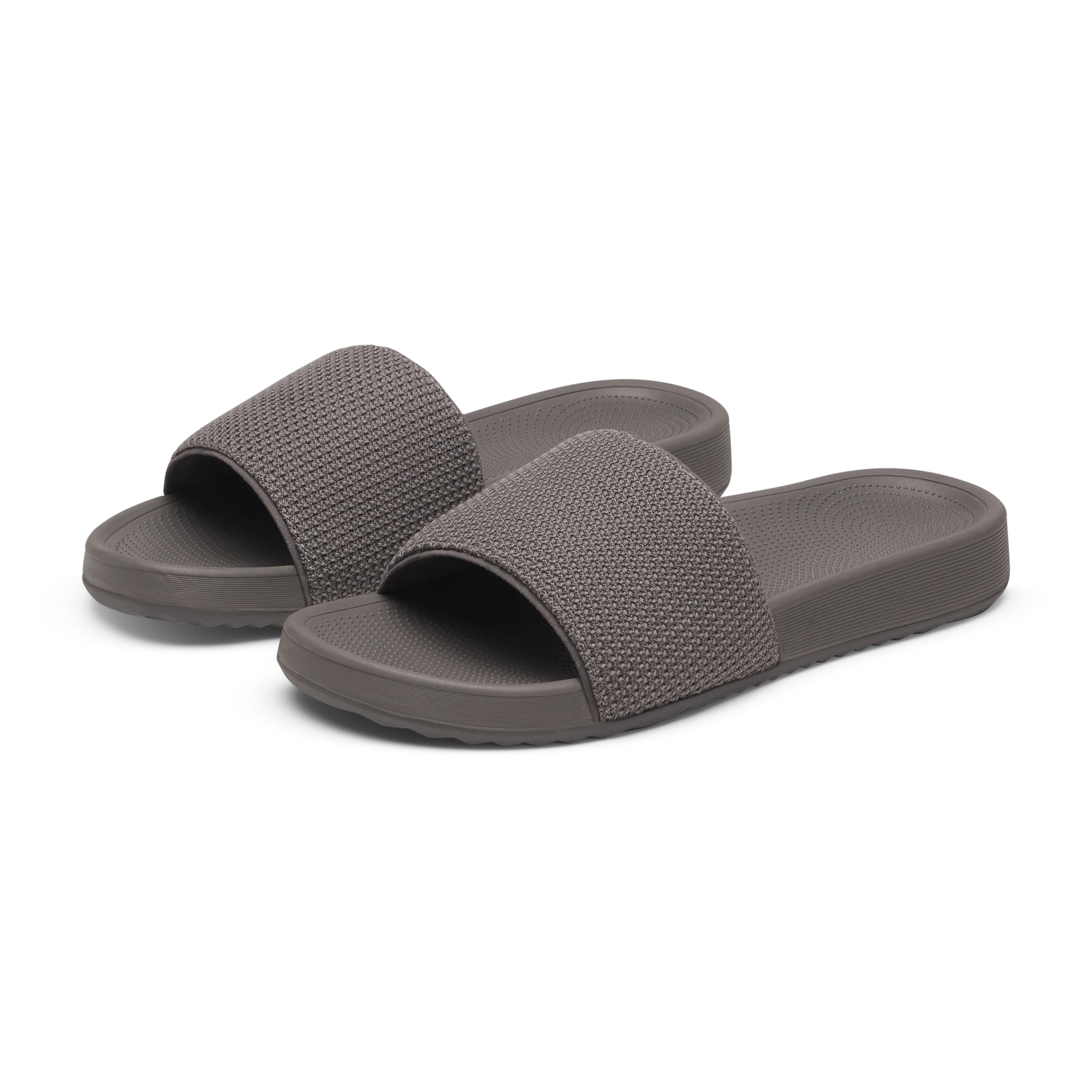 A pair of grey slide sandals with textured woven straps. The soles are smooth with a dotted footbed and ridged sides.
