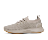 Sneaker with a brown mesh upper and green sole on a white background