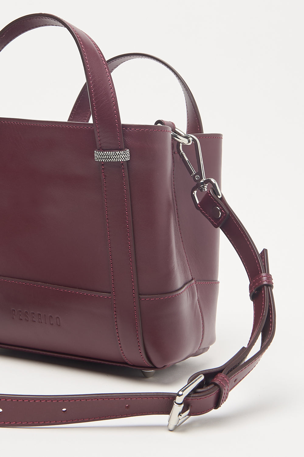 Burgundy leather tote bag with two top handles, a detachable adjustable shoulder strap, and silver-toned hardware.