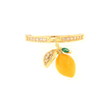 Gold-toned adjustable ring with a yellow enamel lemon charm, clear gemstones on the band, and a small green accent stone.