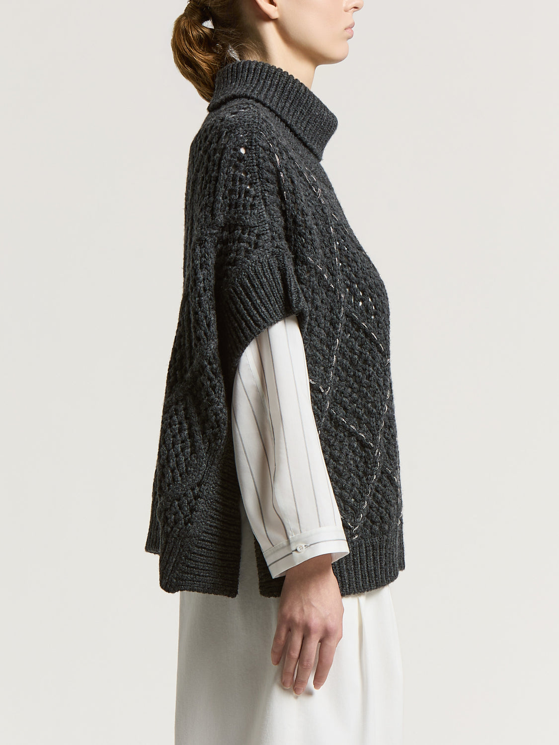 Eclipse gray wool-blend knit cape with a ribbed turtleneck. Features chunky cable knit, openwork details, and light-colored w