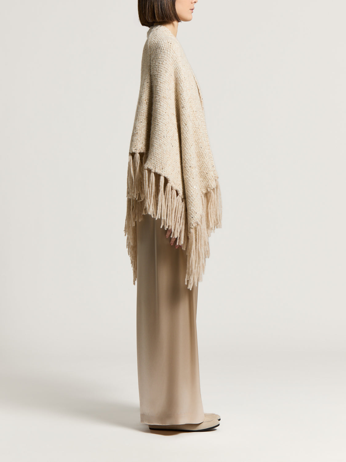 Star dust beige alpaca and wool cape with a textured knit, scattered sequins, and long fringe.