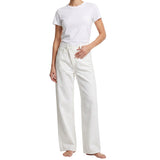 Full-length studio shot of a model wearing the Agolde criss-cross white wide-leg jeans styled with a simple white t-shirt.