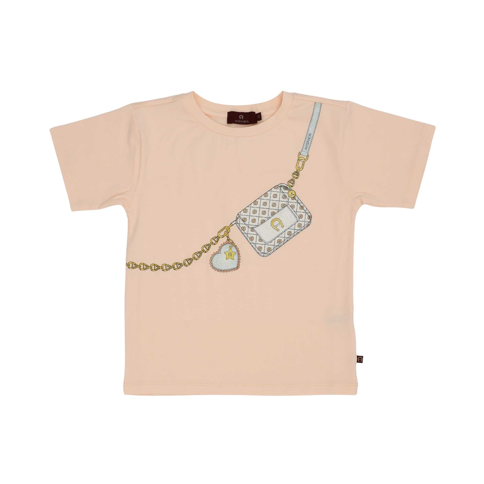 Front view of a peach AIGNER Kids t-shirt featuring a white quilted purse graphic with a gold chain strap and a glittery heart charm.
