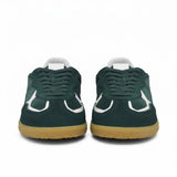 Front face-on view of a pair of ALOHAS forest green suede sneakers highlighting the lace-up closure and white leather curved details on the toe box.