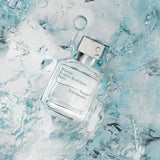 Clear rectangular glass perfume bottle with a silver-toned cap and white text label.