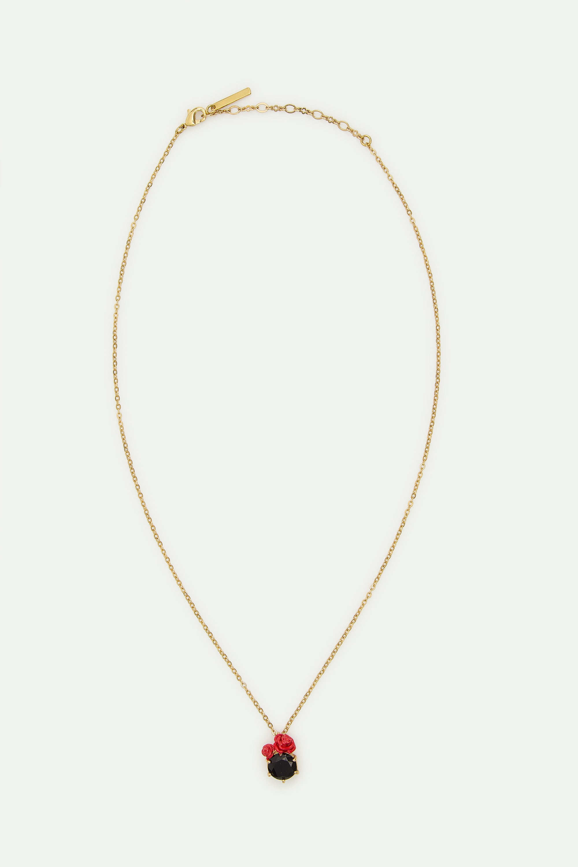 Gold-toned chain necklace with a round black pendant flanked by two small red rose details. Features a lobster clasp.