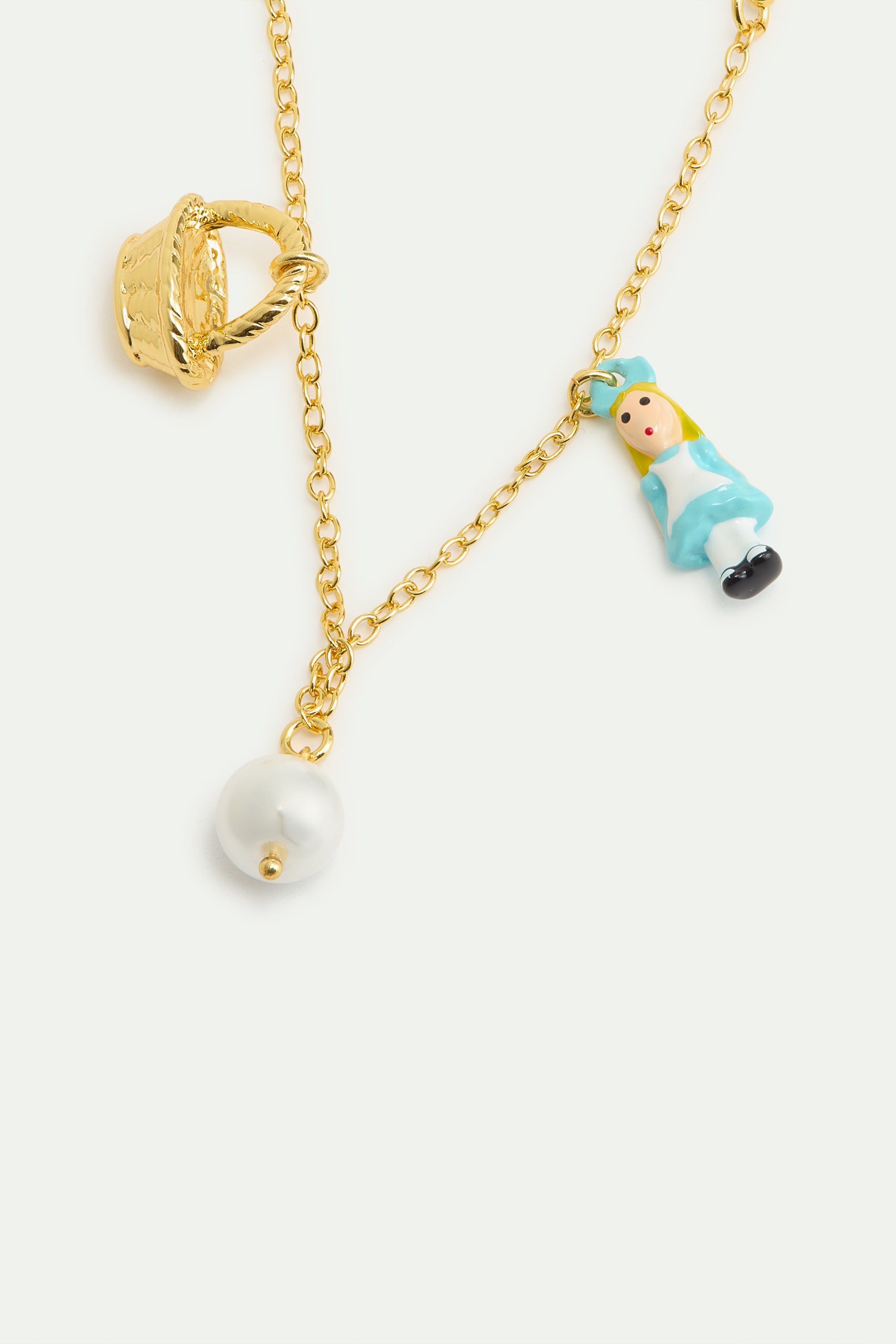 Gold-toned chain bracelet with a textured basket charm, a doll charm in a blue dress, and a white pearl charm.