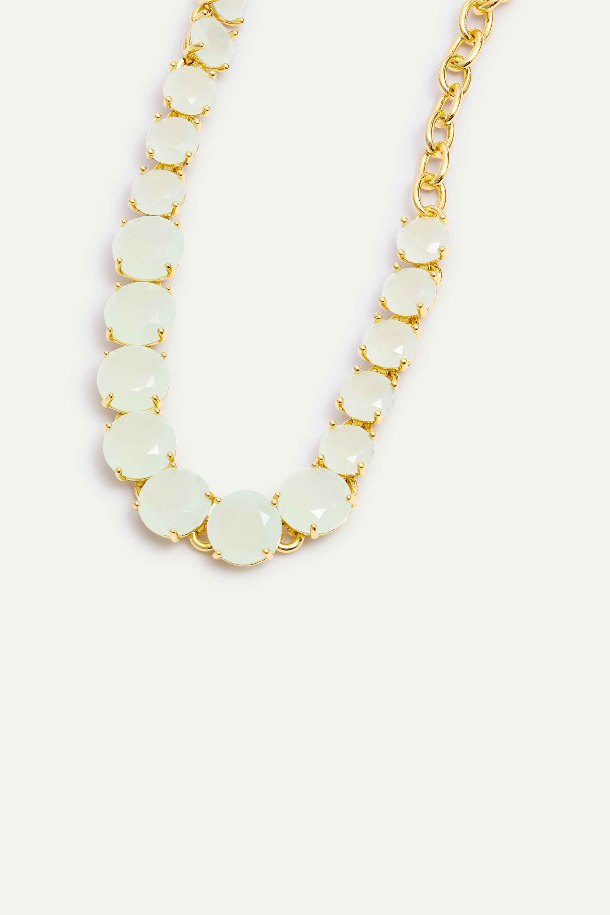 Bracelet with faceted pale green round stones in gold-toned prong settings, graduating in size, connected to a gold-toned cha