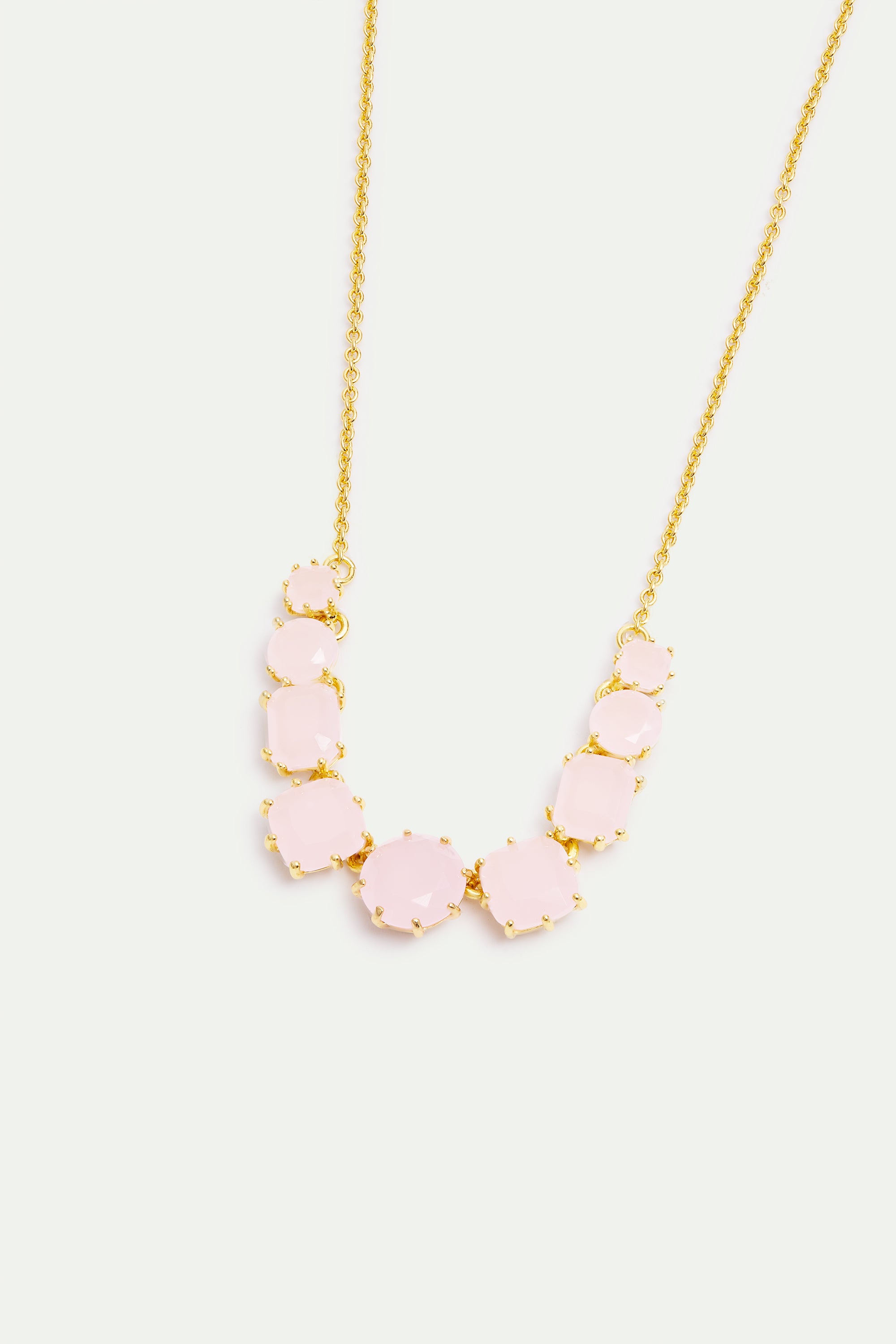 Gold-toned necklace with a curved row of 11 pale pink, faceted stones in varying sizes, set in gold-toned prong settings.
