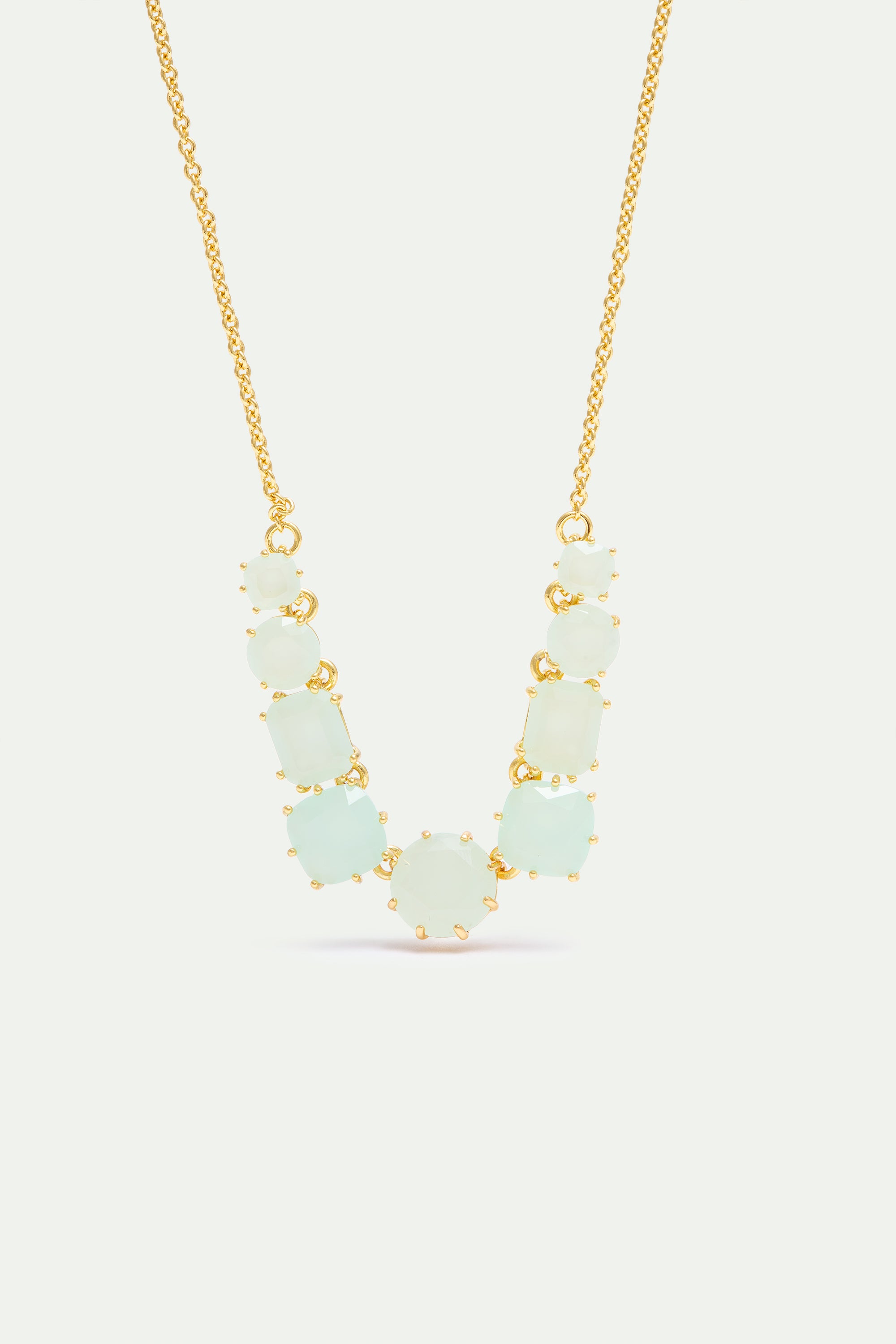 Gold-toned necklace with a graduated arrangement of light green faceted stones in prong settings.