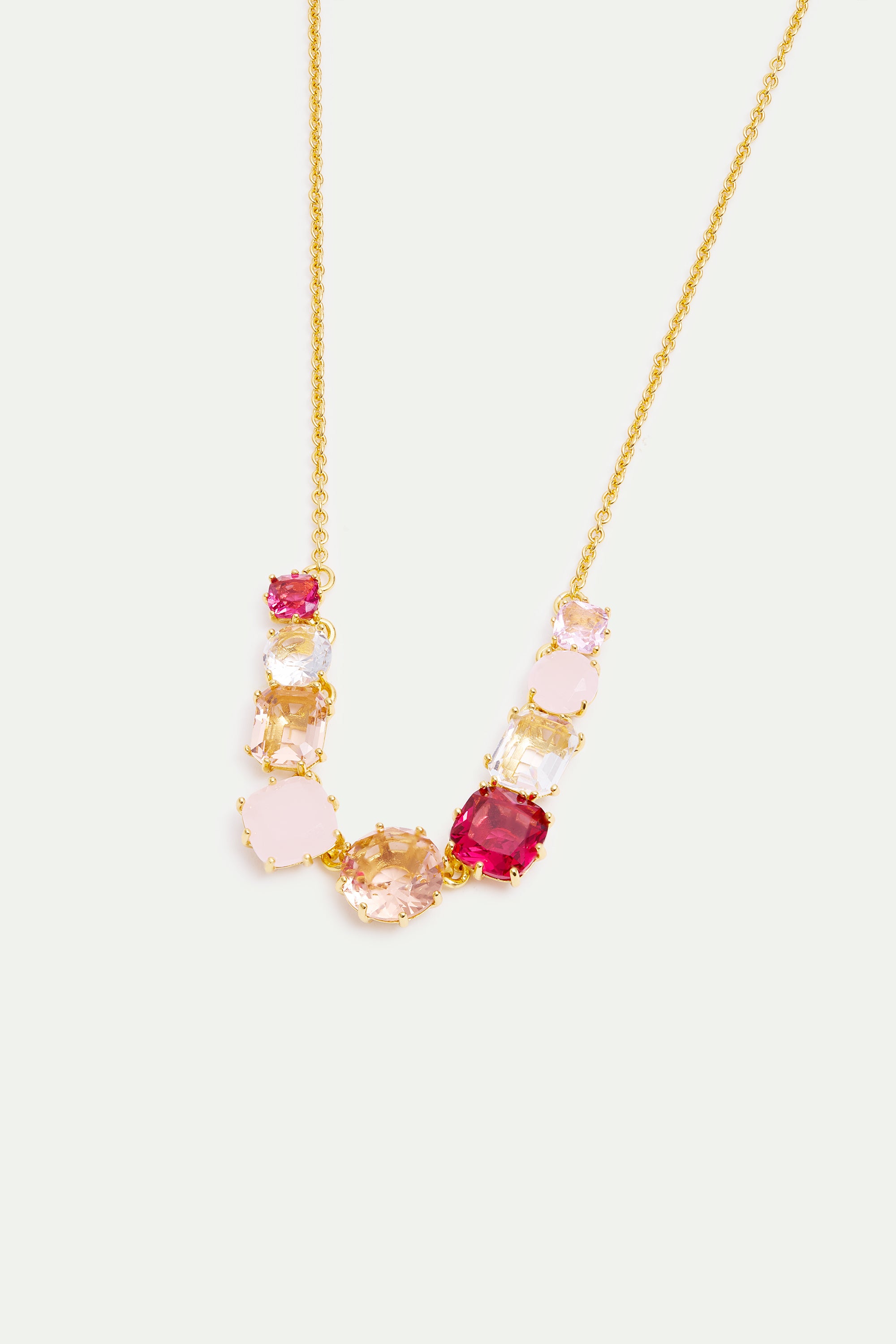 Gold-toned necklace with a curved line of faceted stones: deep pink, light pink, clear, and peach, in cushion and rectangular