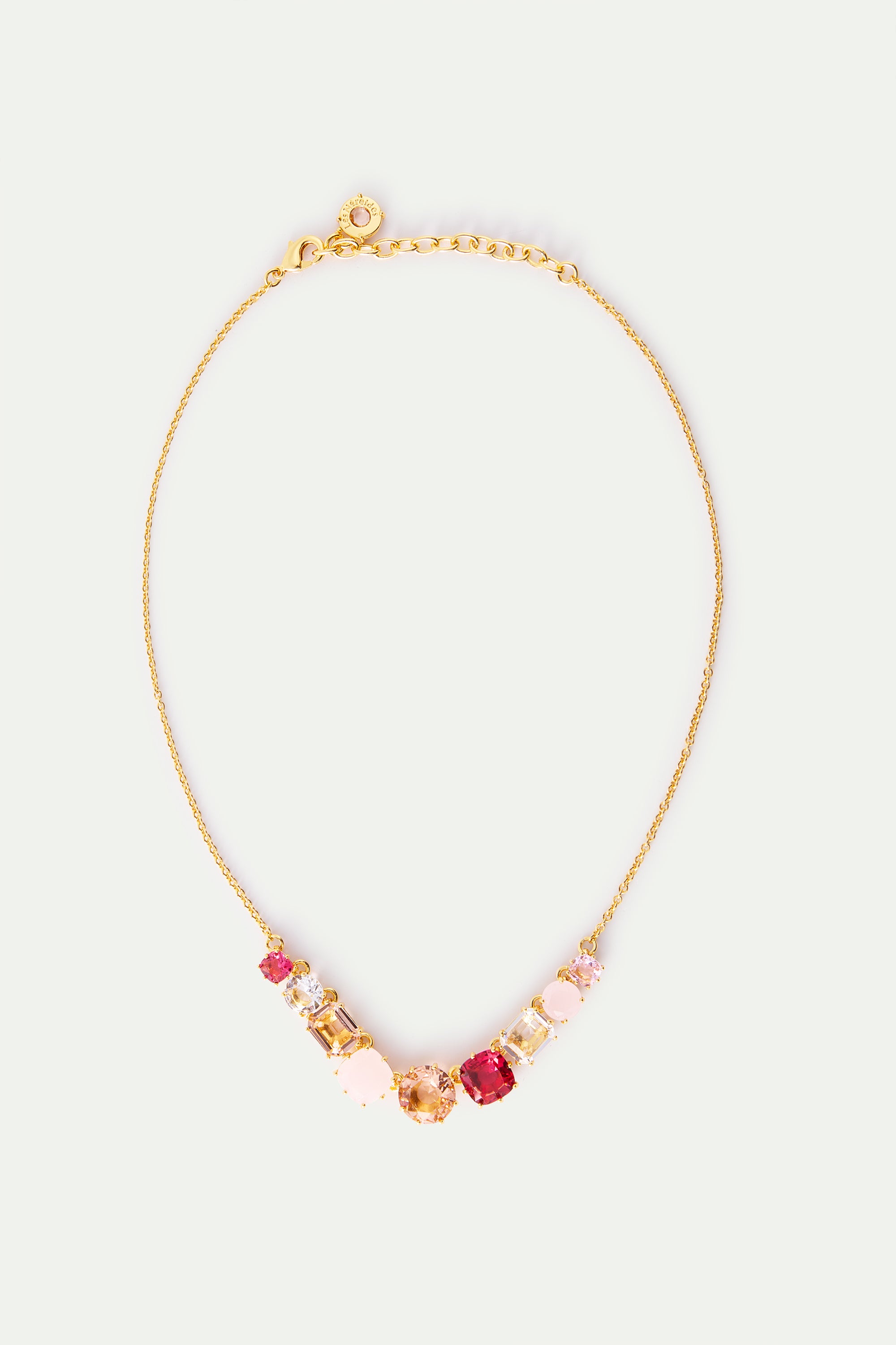 Gold-toned necklace with a curved line of pink, clear, amber, and ruby-red faceted crystals in various shapes.