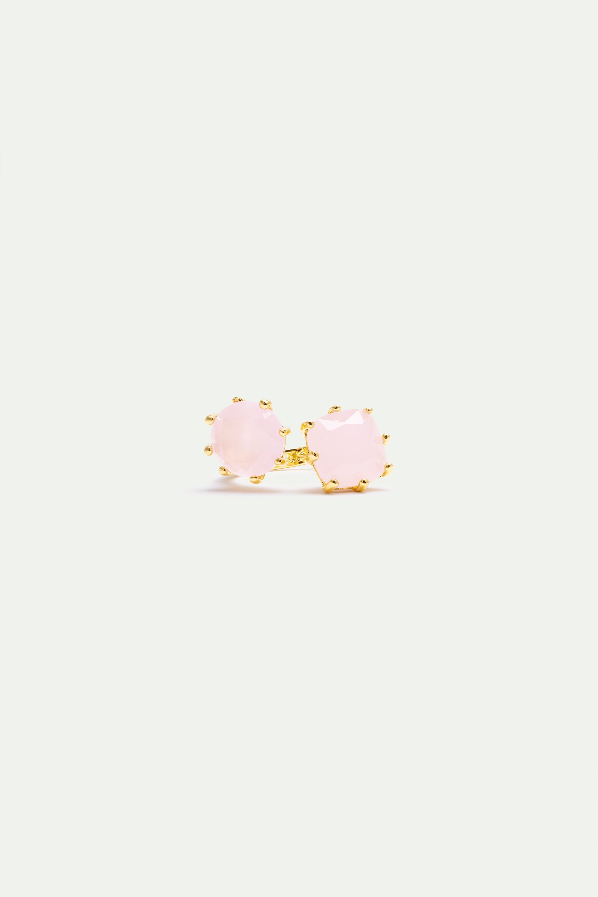 Adjustable ring with two round, faceted pale pink stones, each set in gold-toned prongs on a gold-toned band.