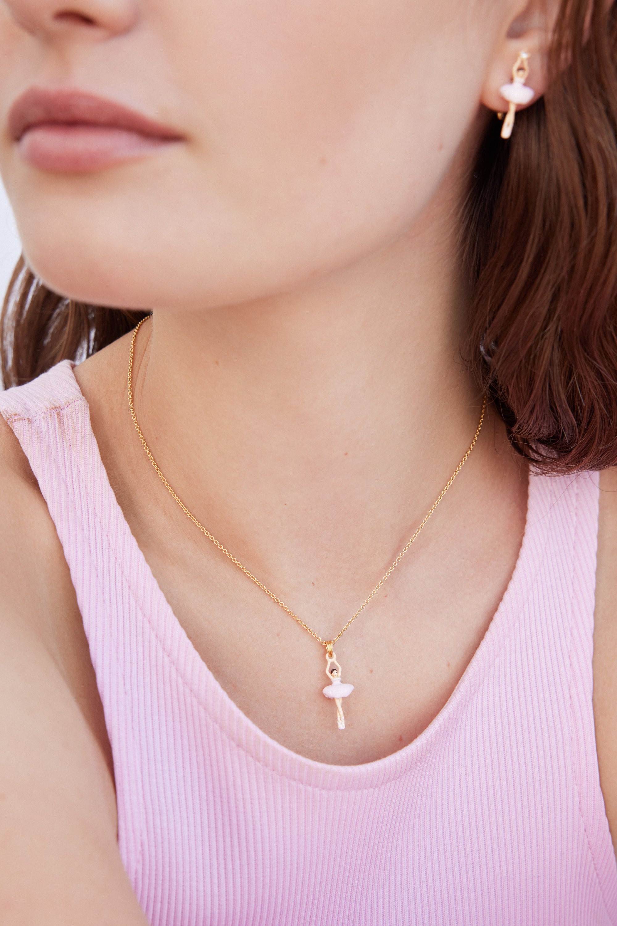 Gold-toned post earring with a ballerina charm. The ballerina has a light pink tutu and white body/legs.
