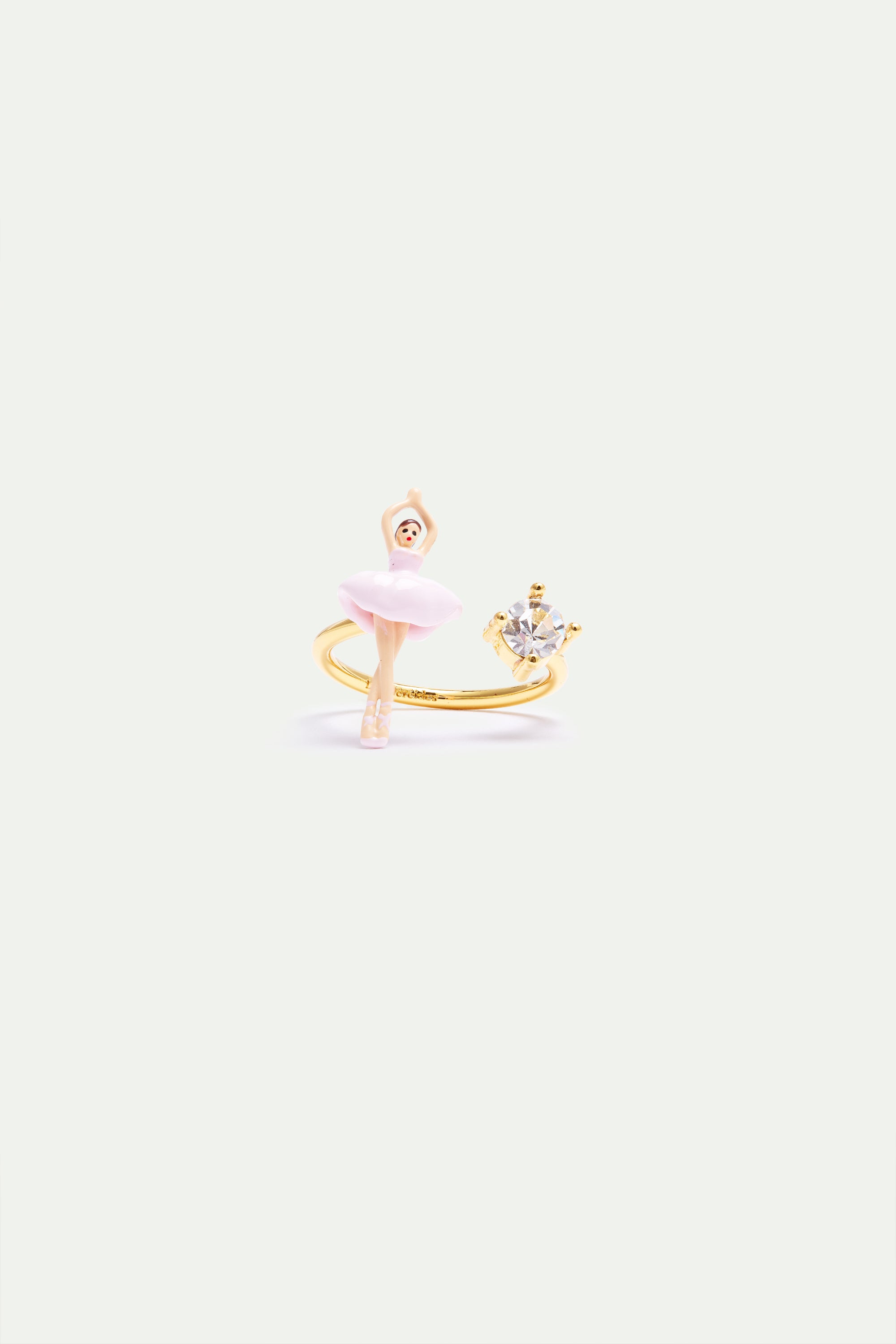 Gold-toned adjustable ring with a pink ballerina figure on one end and a clear faceted stone in a four-prong setting on the o
