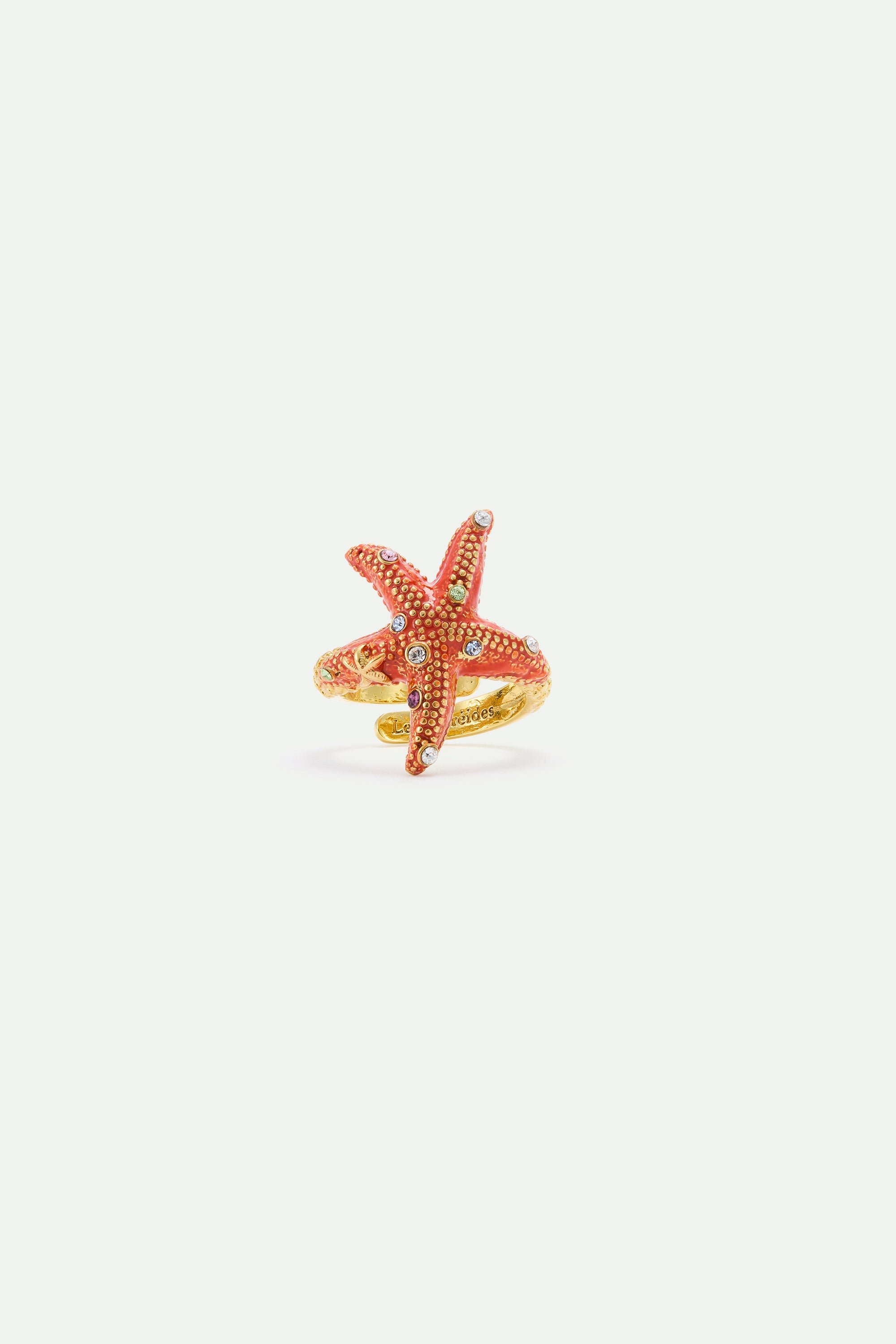Adjustable gold-toned ring featuring a textured reddish-orange starfish embellished with clear and multi-colored rhinestones.